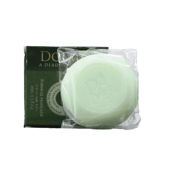 Green circular bar of soap next to its dark green packaging, partially wrapped in clear plastic.