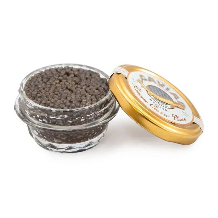 Open glass jar of caviar with a golden lid placed beside it, displaying small black eggs.